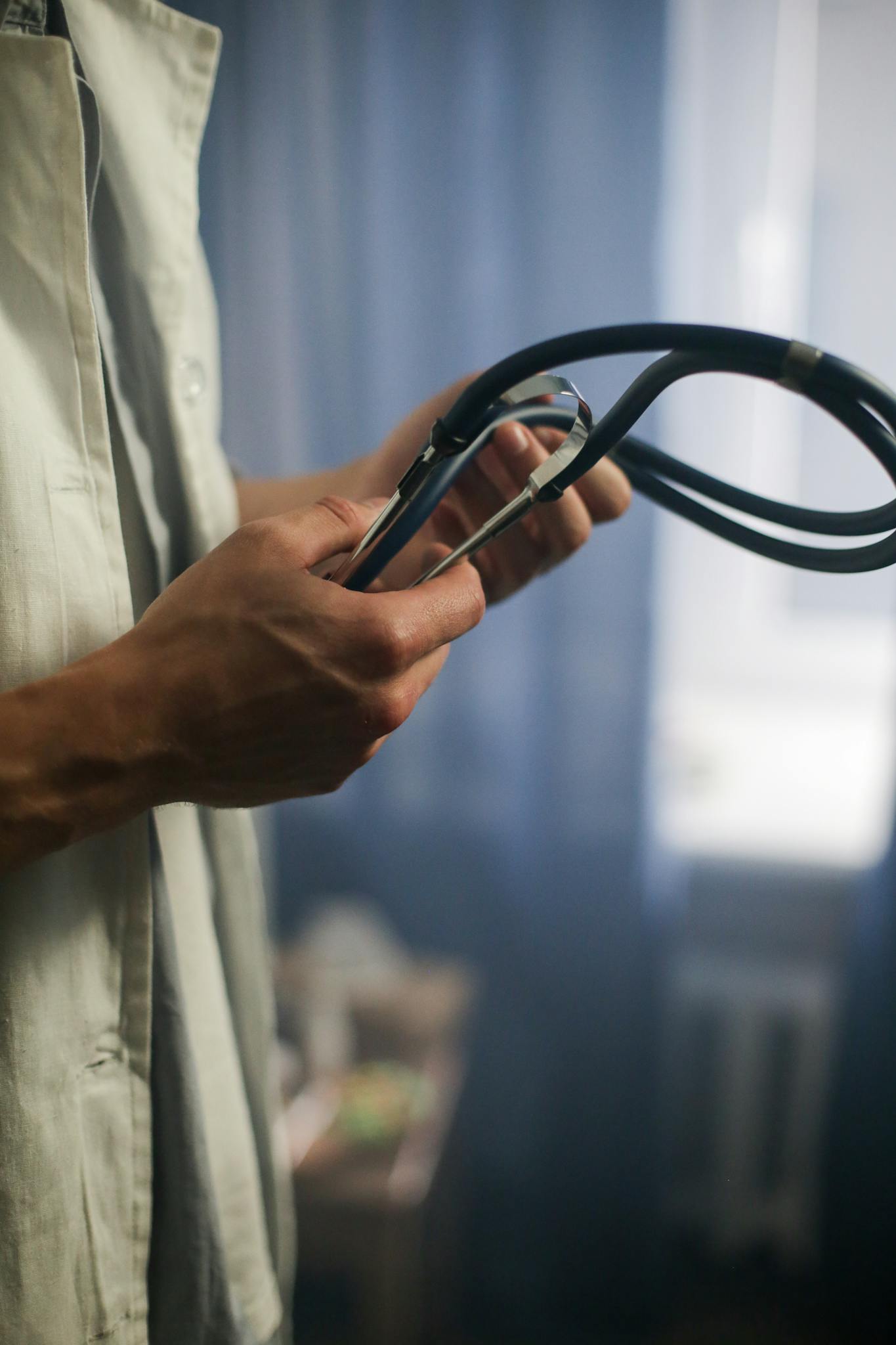 Close-up of a medical professional holding a stethoscope indoors with blurred background.